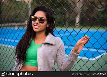 Woman wearing sunglasses over tennis court background