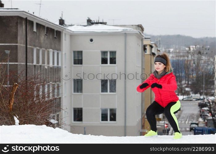 Woman wearing warm sportswear running jogging outside during winter in front of urban city street. Outdoor sport exercises, sporty outfit ideas.. Woman exercising during winter