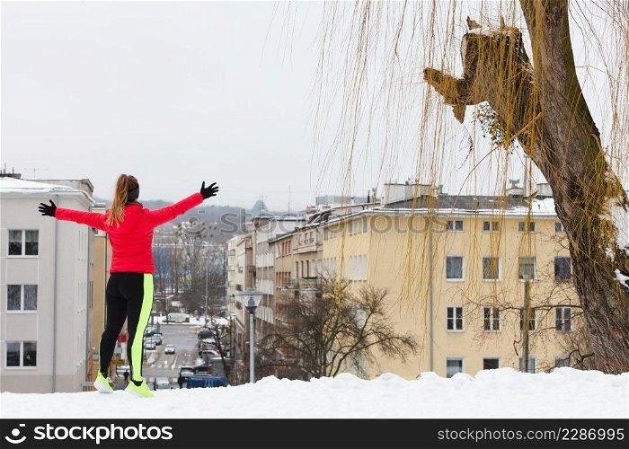 Woman wearing warm sportswear running jogging outside during winter in front of urban city street. Outdoor sport exercises, sporty outfit ideas.. Woman exercising during winter