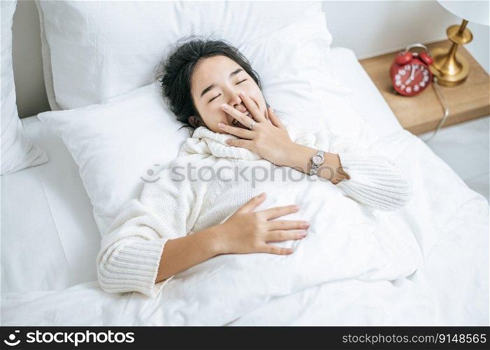 Woman wearing white shirt sleeping on the bed and white pillows.
