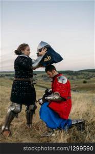 Woman wears a helmet to medieval knight, great tournament. Armored ancient warrior in armour posing in the field