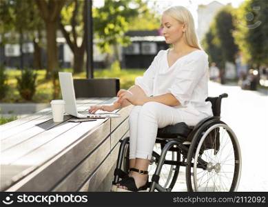 woman wheelchair using laptop outdoors