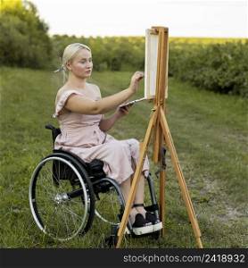 woman wheelchair with canvas palette painting outdoors