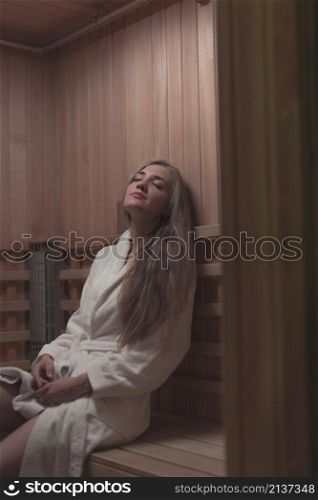 woman white bathrobe sitting wooden bench relaxing sauna