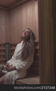 woman white bathrobe sitting wooden bench relaxing sauna
