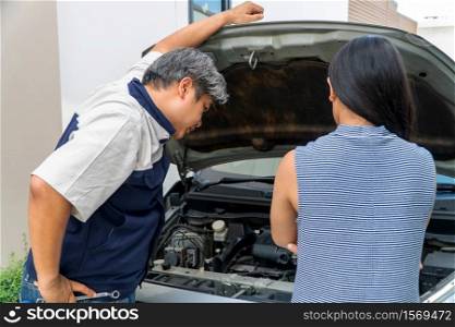 woman who owns the car standing and looking for auto mechanic Check the engine to find the cause.