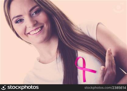 Woman wih pink cancer ribbon on chest. Healthcare, medicine and breast cancer awareness concept, toned image. Woman wih pink cancer ribbon on chest