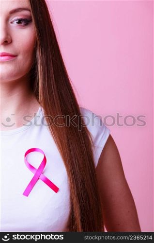 Woman wih pink cancer ribbon on chest. Healthcare, medicine and breast cancer awareness concept. Studio shot, pink light red background. Woman wih pink cancer ribbon on chest