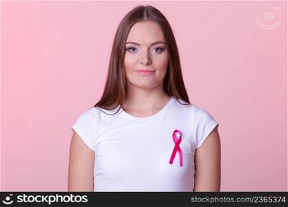 Woman wih pink cancer ribbon on chest. Healthcare, medicine and breast cancer awareness concept. Studio shot, pink light red background. Woman wih pink cancer ribbon on chest