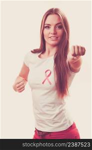 Woman wih pink ribbon on chest punching boxing. Fight against disease. Healthcare, medicine and breast cancer awareness concept, toned image. Woman wih pink ribbon on chest punching boxing