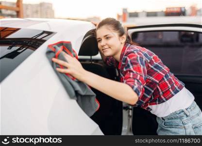 Woman wipes automobile after washing on self-service car wash. Lady cleaning vehicle. Woman wipes automobile, self-service car wash
