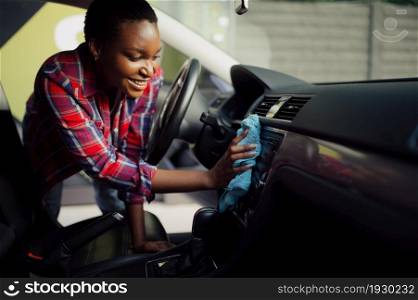 Woman wipes car interior with a rag, hand auto wash station. Car-wash industry or business. Female person cleans her vehicle from dirt outdoors. Woman wipes car interior with rag, hand auto wash