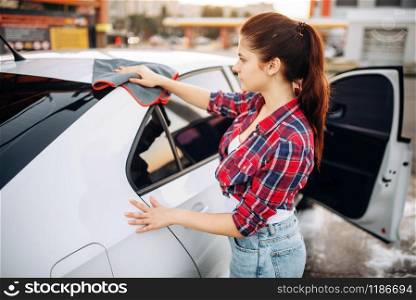 Woman wipes the car with a cloth after washing, polishing process on self-service car-wash. Lady cleaning vehicle