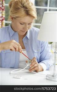 Woman Wiring Electrical Plug On Lamp At Home