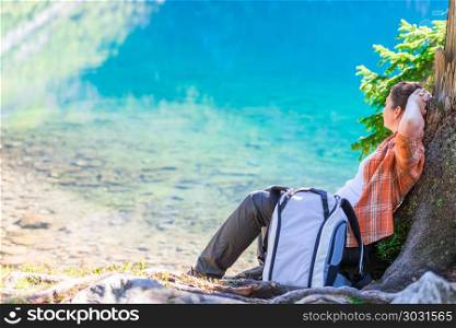 woman with a backpack relaxes and rests by the lake in the mount. woman with a backpack relaxes and rests by the lake in the mountains