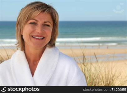 Woman with a bathrobe on the beach