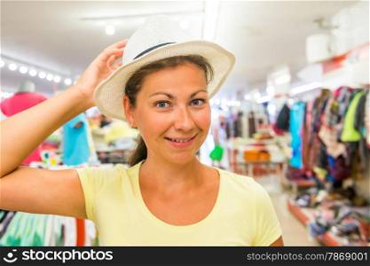 woman with a beautiful smile at the store chooses hat