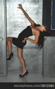 Woman with a black dress standing in front of a metal wall.