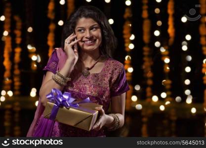 Woman with a gift talking on a mobile phone