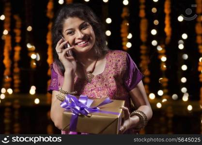 Woman with a gift talking on a mobile phone