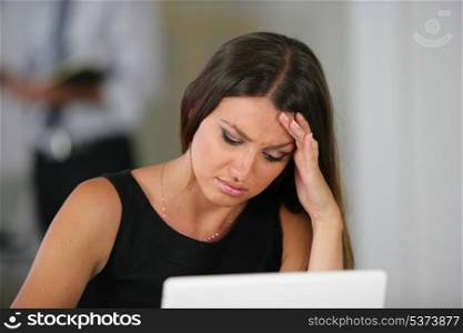 Woman with a headache at her laptop