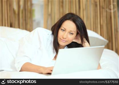 Woman with a laptop on her bed