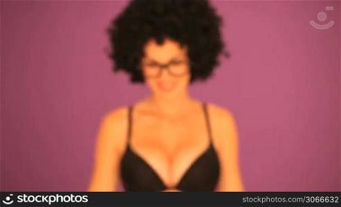 Woman with a large curly black afro hairstyle and glasses stepping into focus against a purple background