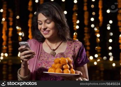 Woman with a plate of sweets reading an sms