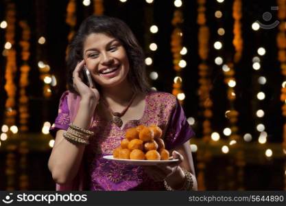 Woman with a plate of sweets talking on mobile phone