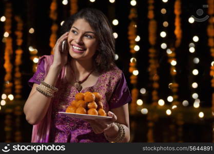 Woman with a plate of sweets talking on mobile phone