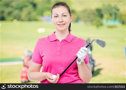 woman with a stick and a ball for golf in the studio on a background of golf courses