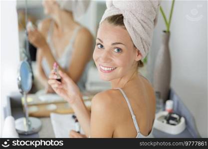woman with a towel on her head doing her make-up