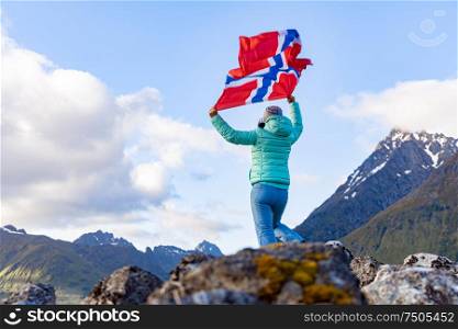 Woman with a waving flag of Norway on the background of nature