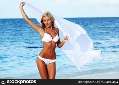 woman with a white fabric in his hands on the beach