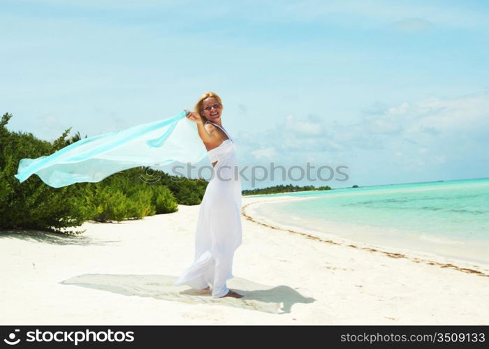 woman with a white fabric in his hands on the beach