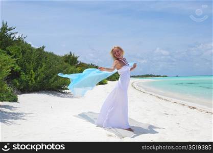 woman with a white fabric in his hands on the beach