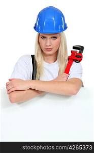 Woman with a wrench and board left blank for your message