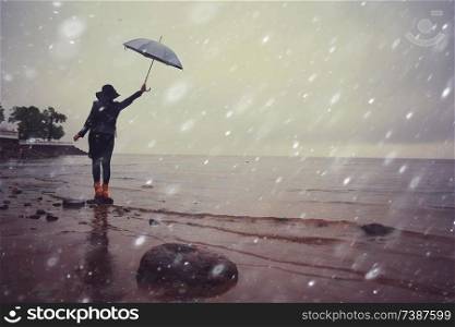 woman with an umbrella by the sea wind rain