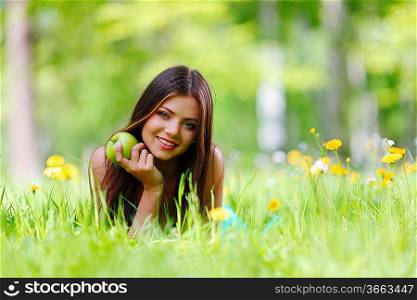 Woman with apple laying on green grass