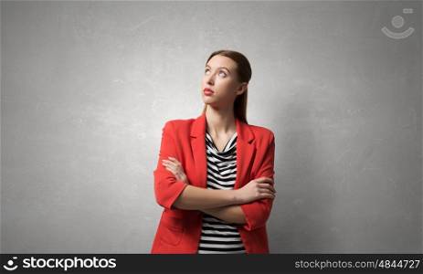 Woman with arms crossed on chest. Young pretty woman in red jacket looking thoughtfully away