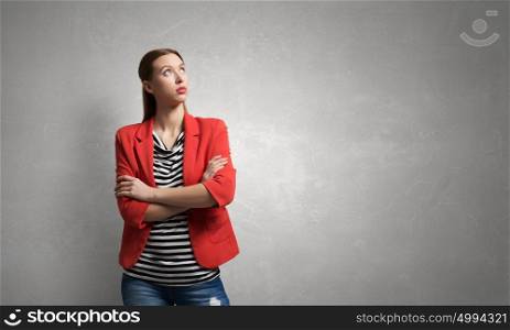 Woman with arms crossed on chest. Young pretty woman in red jacket looking thoughtfully away