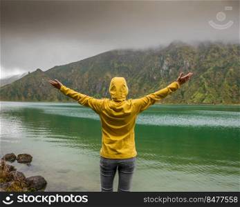 Woman with arms raisaed feeling the nature and enjoying the lake view