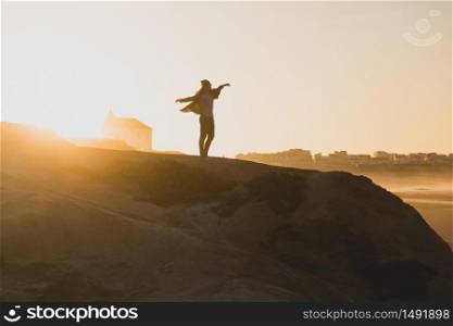 Woman with arms raised enjoying the view at sunset