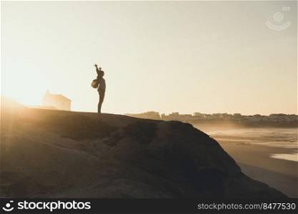 Woman with arms raised enjoying the view at sunset