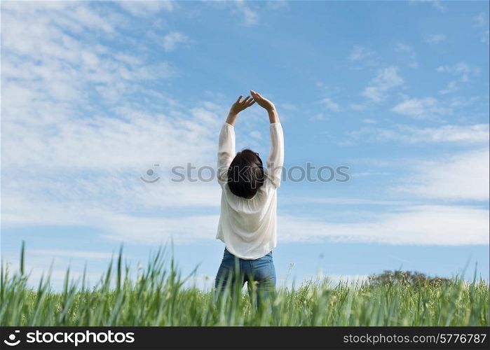 Woman with arms up in green field