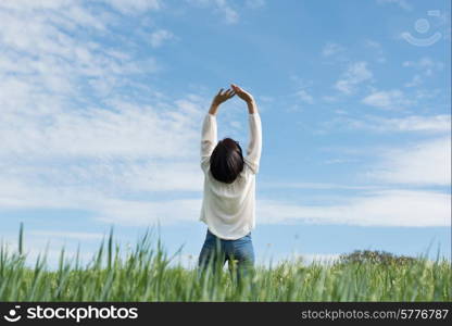 Woman with arms up in green field