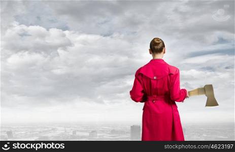 Woman with axe. Rear view of woman in red coat with axe in hands