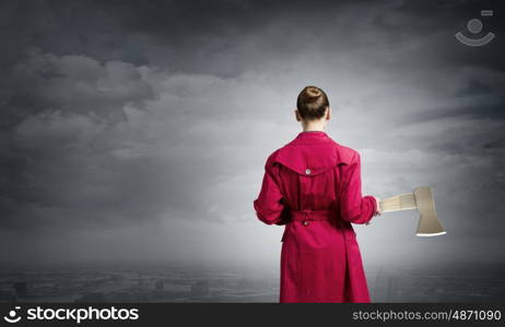 Woman with axe. Rear view of woman in red coat with axe in hands