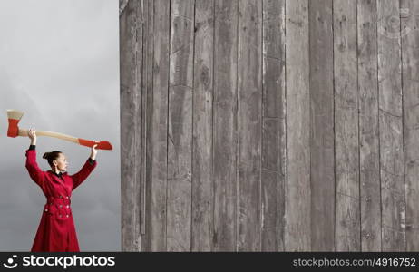 Woman with axe. Young woman in red coat with axe in hands