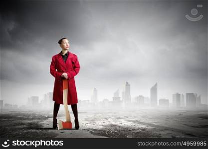 Woman with axe. Young woman in red coat with axe in hands